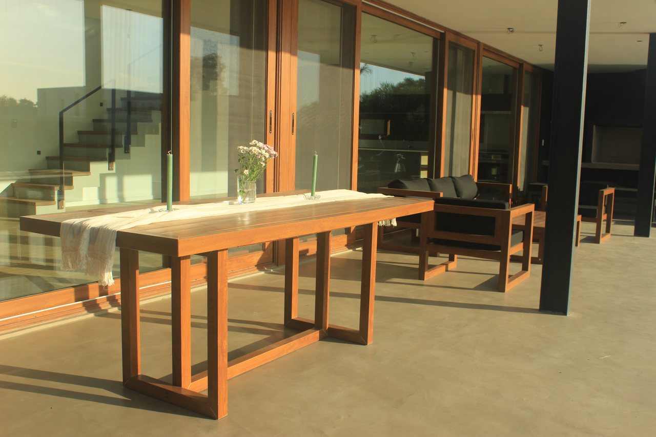 Mesa de exterior Velenza frente a grandes aberturas de madera