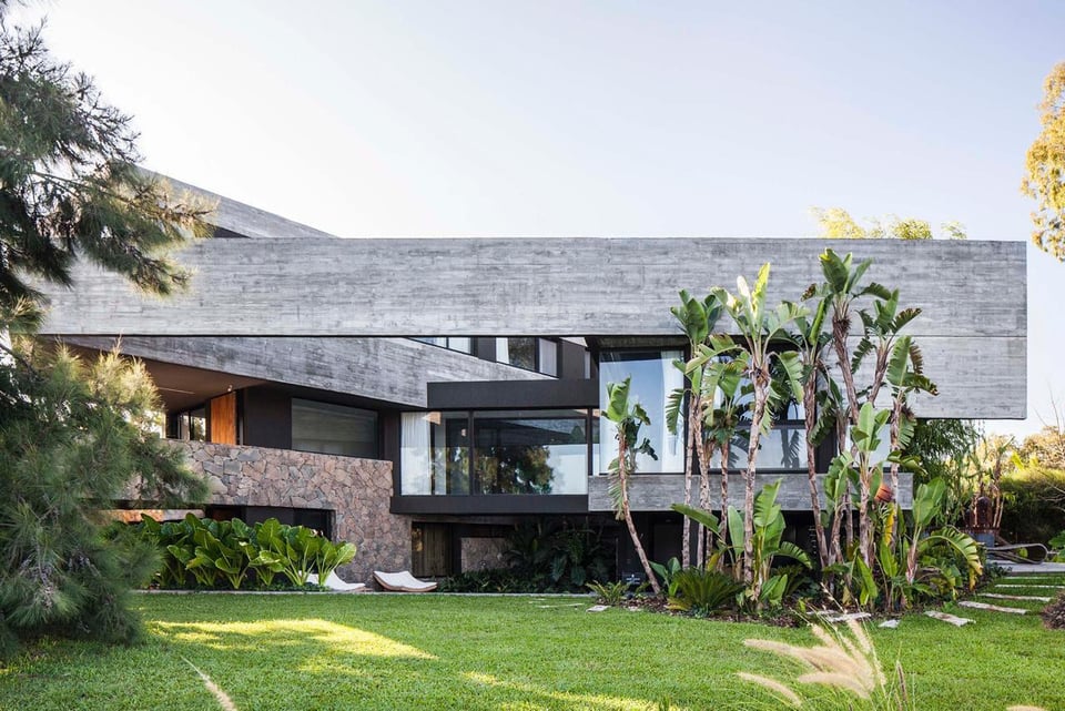 Casa contemporánea con voladizos de hormigón y jardín tropical