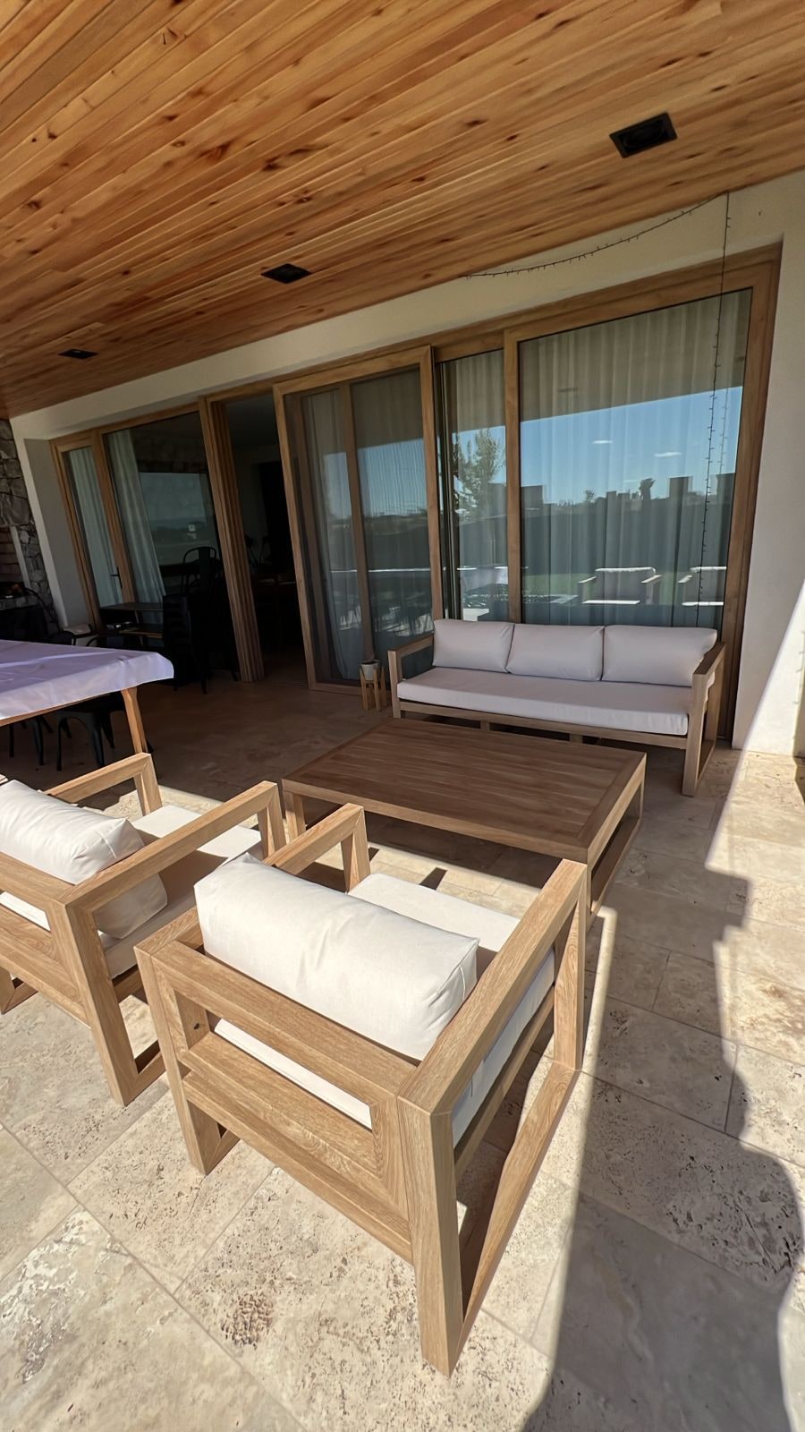 Conjunto de muebles de exterior con tapizado náutico claro en terraza con techo de madera — Velenza